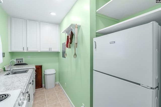 interior space featuring white appliances, light tile patterned floors, white cabinets, sink, and light stone counters