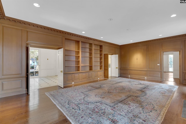 living room featuring built in features, light hardwood / wood-style flooring, and ornamental molding