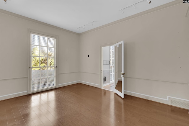 unfurnished room with track lighting, hardwood / wood-style flooring, and crown molding