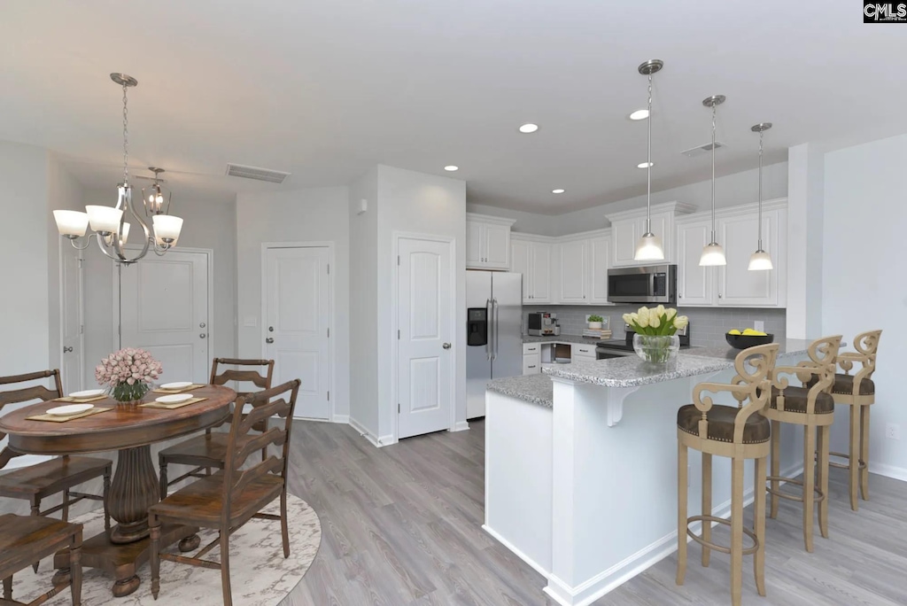 kitchen featuring stainless steel appliances, white cabinetry, kitchen peninsula, and backsplash