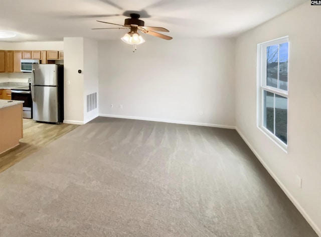 unfurnished living room featuring ceiling fan and light colored carpet