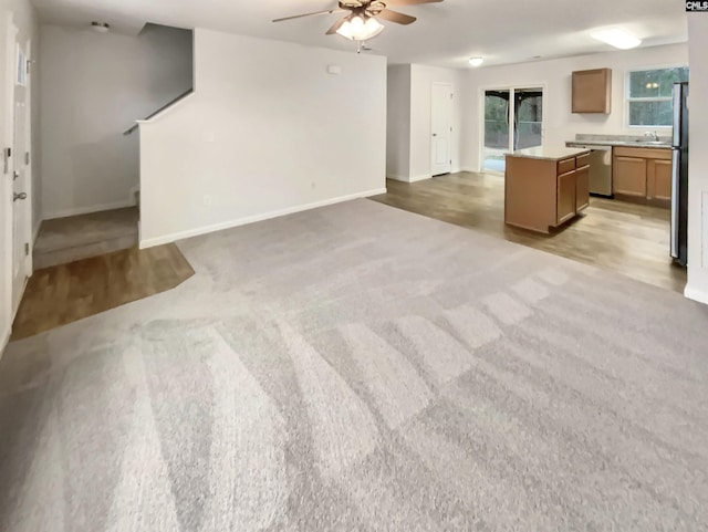 unfurnished living room featuring light carpet, sink, and ceiling fan