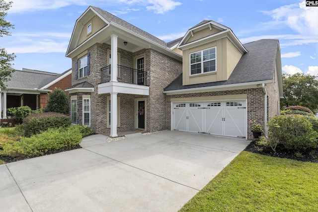 view of front of home featuring a garage, a front lawn, and a balcony