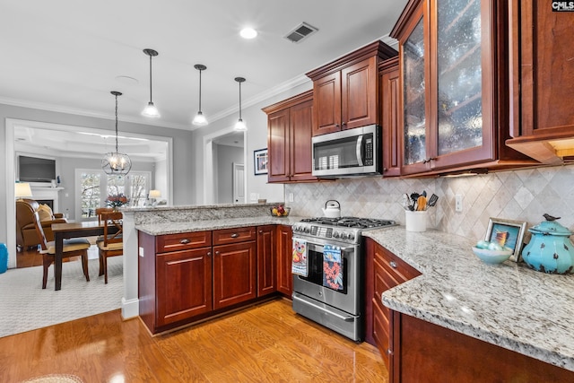 kitchen featuring crown molding, light hardwood / wood-style floors, appliances with stainless steel finishes, tasteful backsplash, and decorative light fixtures