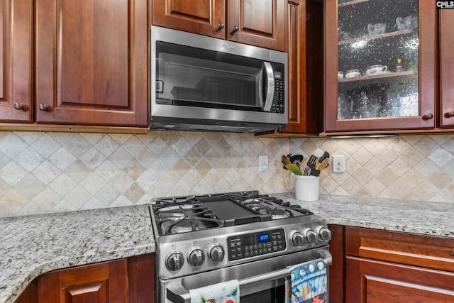 kitchen featuring light stone counters, backsplash, and appliances with stainless steel finishes