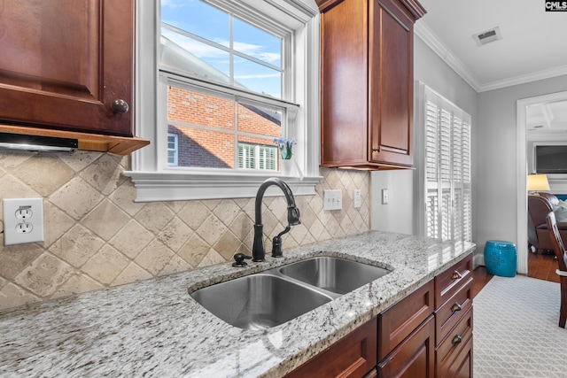 kitchen featuring sink, decorative backsplash, light stone countertops, and ornamental molding