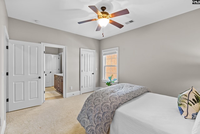 bedroom with a closet, light colored carpet, connected bathroom, and ceiling fan