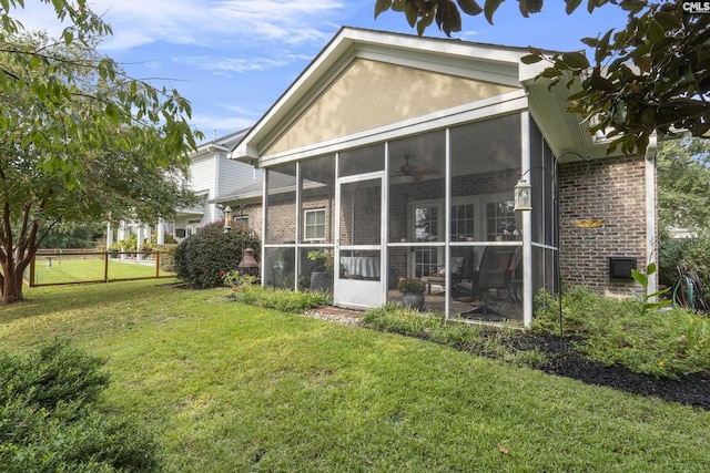 rear view of property featuring a sunroom and a yard