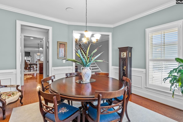 dining area featuring wood-type flooring, crown molding, and a notable chandelier