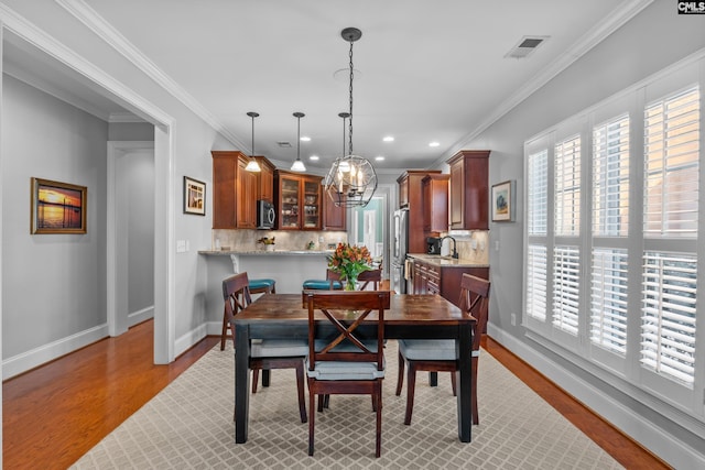 dining area with light wood-type flooring and crown molding