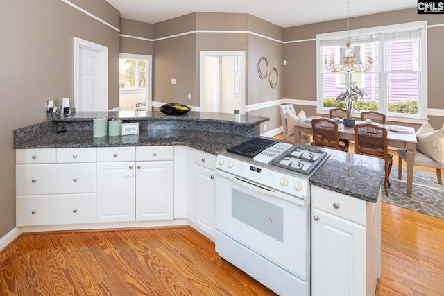 kitchen featuring white cabinetry, white gas stove, hanging light fixtures, and kitchen peninsula