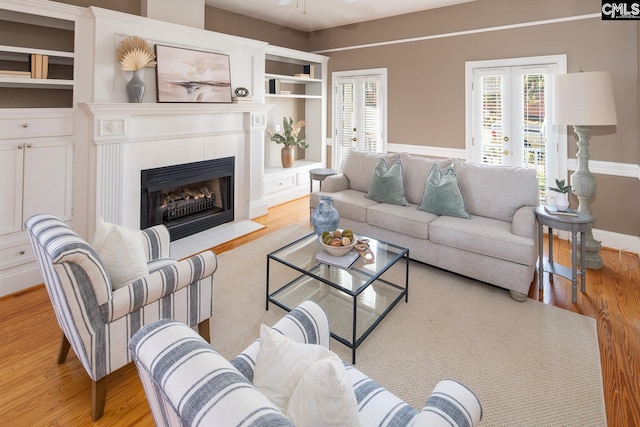 living room featuring light wood-type flooring, french doors, and a fireplace