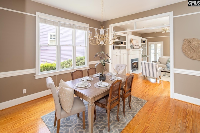 dining space featuring light wood-type flooring and ceiling fan with notable chandelier