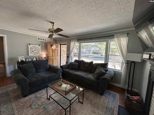 living room featuring a textured ceiling, dark hardwood / wood-style flooring, ornamental molding, and a fireplace