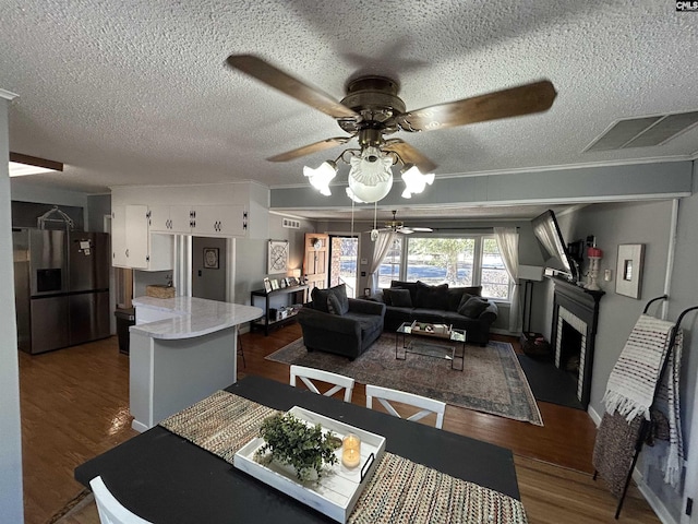 dining space featuring dark wood-type flooring, a textured ceiling, ceiling fan, and ornamental molding