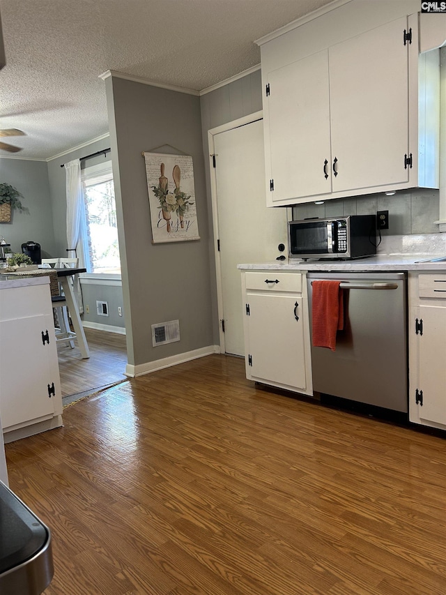 kitchen featuring hardwood / wood-style floors, a textured ceiling, white cabinetry, stainless steel appliances, and crown molding