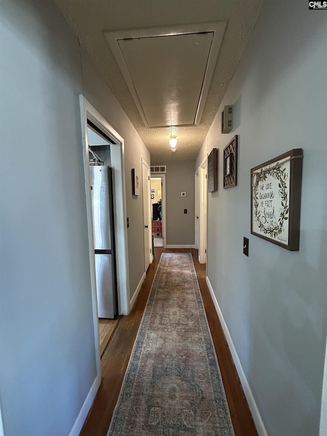 hallway with dark hardwood / wood-style floors and a textured ceiling