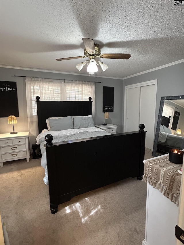 carpeted bedroom with ceiling fan, a textured ceiling, a closet, and ornamental molding