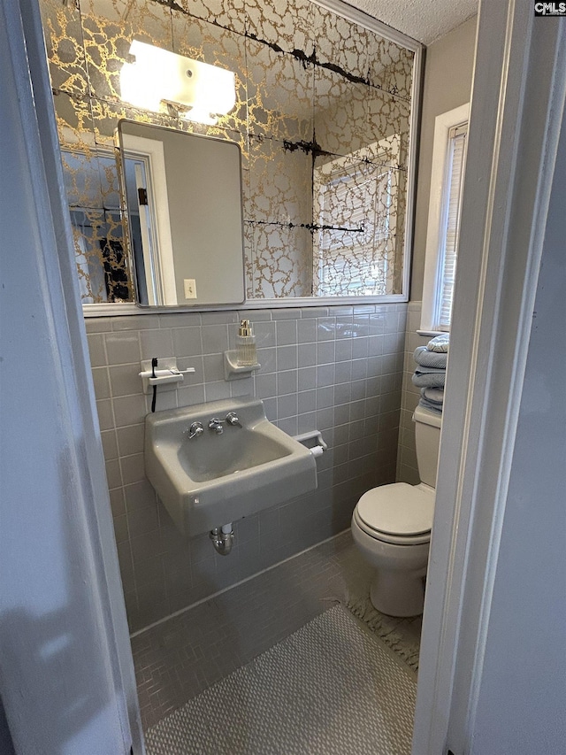 bathroom with sink, toilet, tile walls, and tile patterned floors