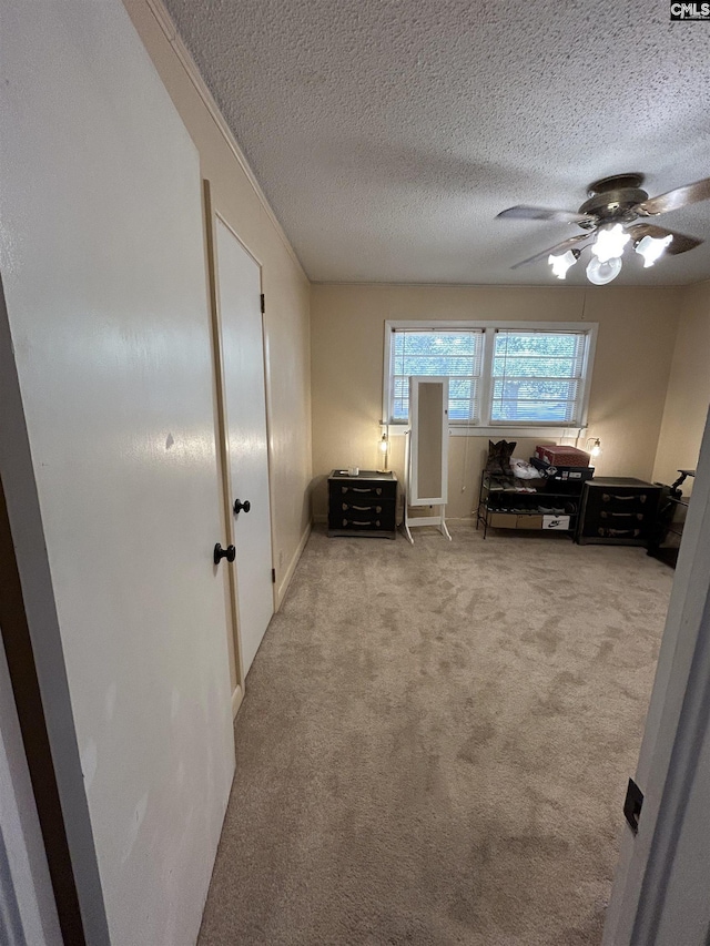 bedroom featuring ceiling fan, a textured ceiling, and light carpet