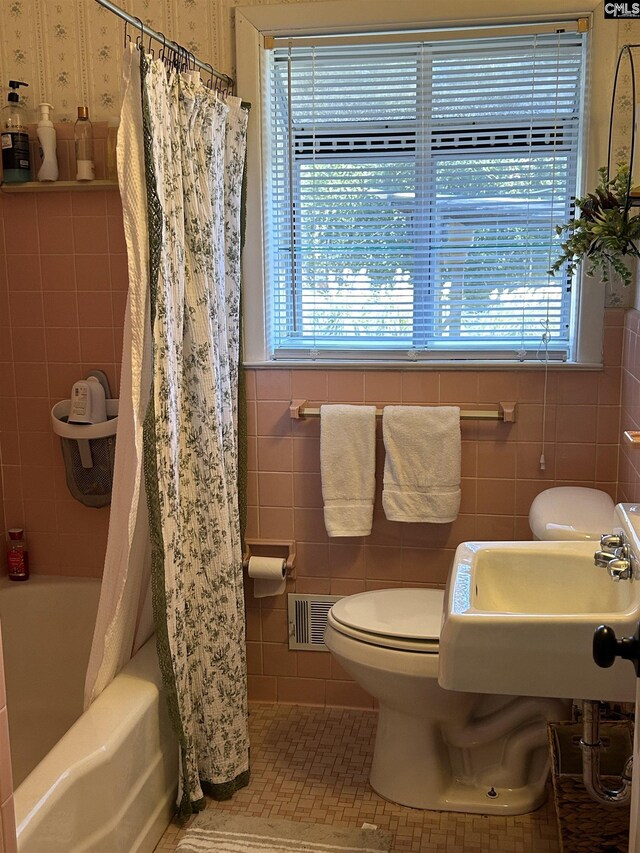 full bathroom featuring tile patterned flooring, tile walls, sink, toilet, and shower / bath combo with shower curtain