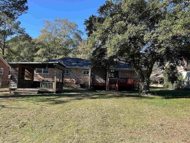 rear view of property featuring a deck and a yard