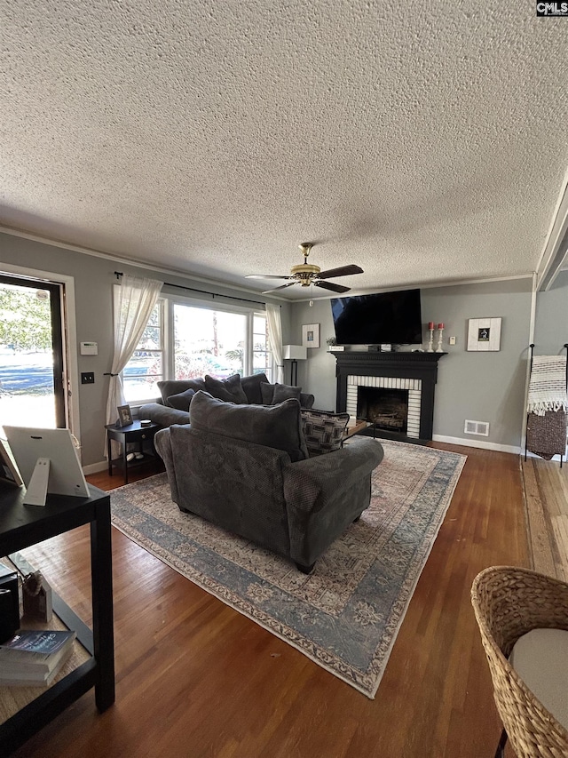 living room featuring ceiling fan, a textured ceiling, dark hardwood / wood-style floors, and a fireplace