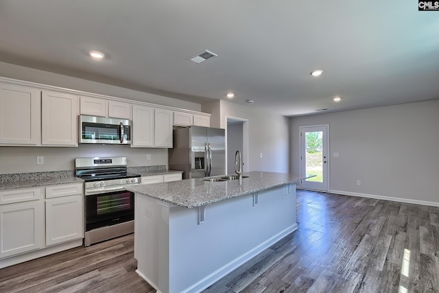 kitchen featuring white cabinets, sink, a breakfast bar, stainless steel appliances, and a center island with sink