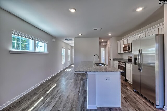 kitchen with sink, stainless steel appliances, white cabinetry, and a center island with sink