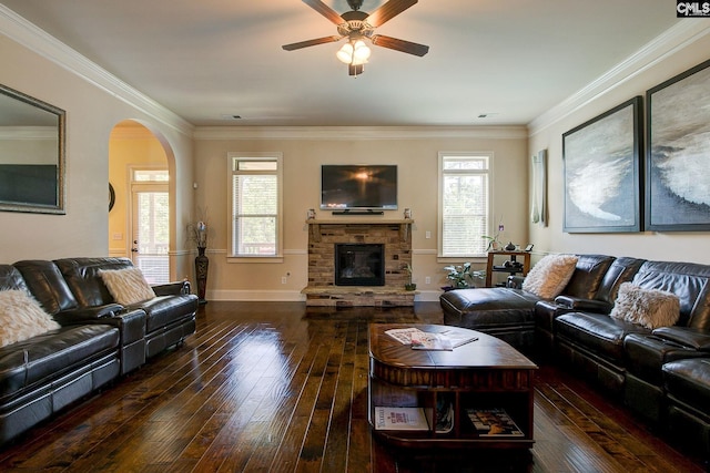 living room featuring ceiling fan, dark hardwood / wood-style floors, ornamental molding, and a stone fireplace