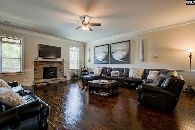 living room featuring ceiling fan, dark hardwood / wood-style flooring, ornamental molding, and a stone fireplace