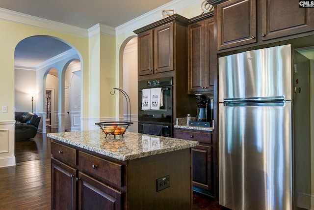kitchen with dark brown cabinetry, a center island, and stainless steel refrigerator