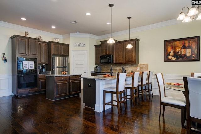 kitchen with black appliances, decorative light fixtures, light stone counters, and ornamental molding