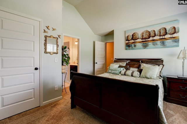 carpeted bedroom featuring lofted ceiling and ensuite bathroom