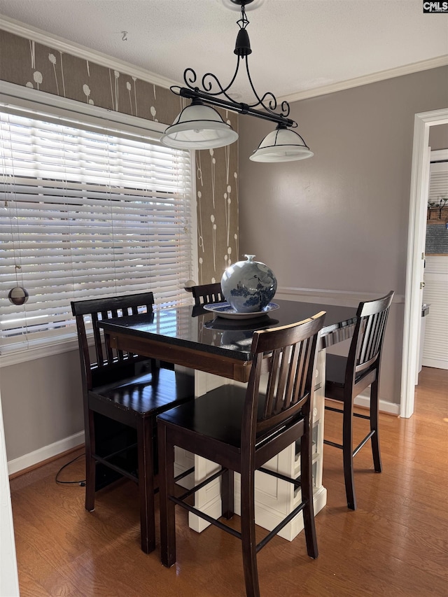 dining space with hardwood / wood-style flooring and crown molding