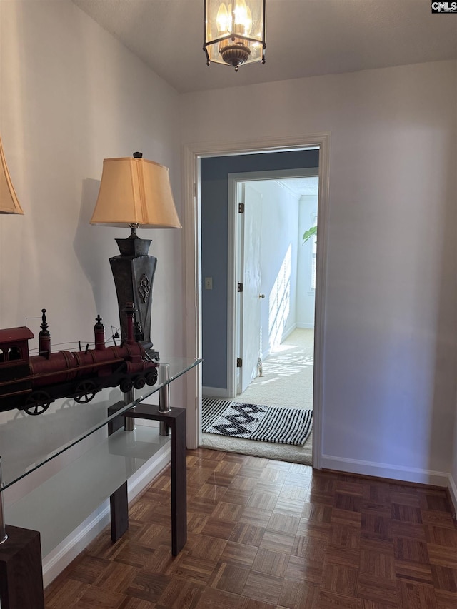 entryway featuring dark parquet floors and an inviting chandelier