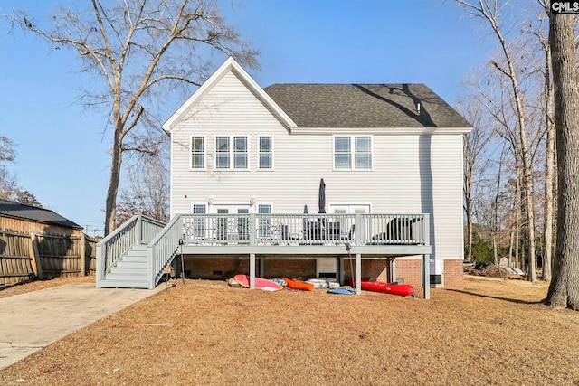 back of property featuring a deck and a lawn