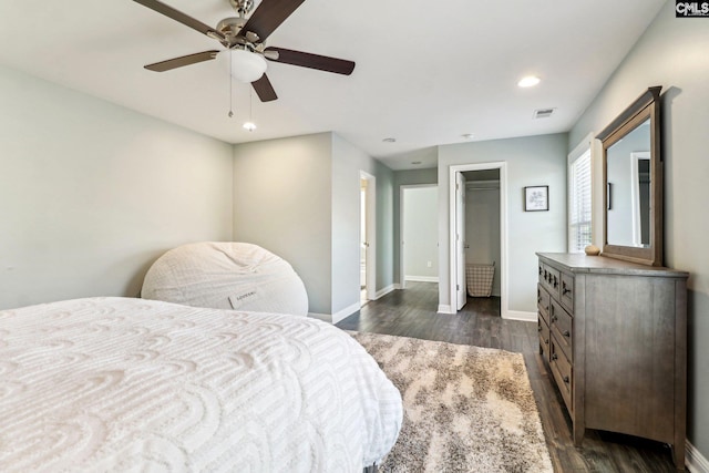 bedroom with dark wood-type flooring, a closet, a spacious closet, and ceiling fan