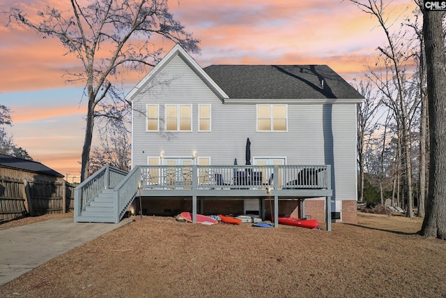 back house at dusk with a yard and a deck