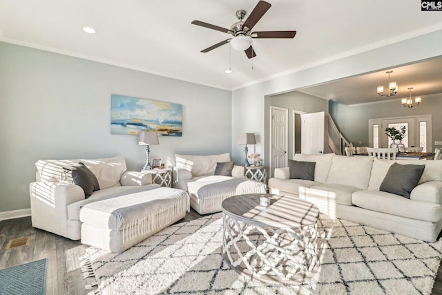 living room with hardwood / wood-style flooring, ceiling fan with notable chandelier, and crown molding