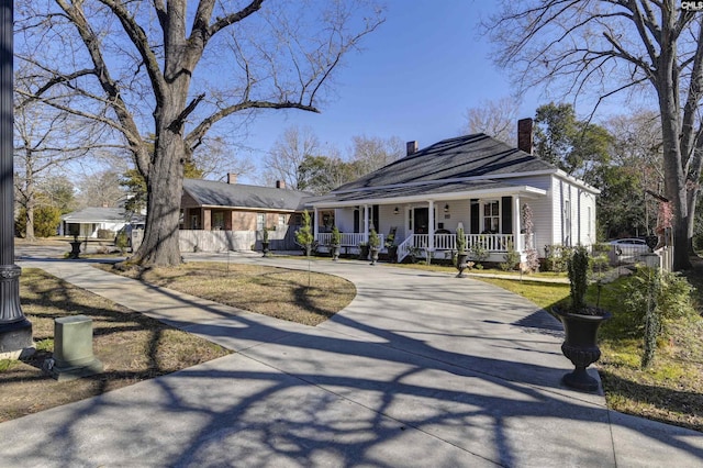 view of front of property with a porch, concrete driveway, and a chimney