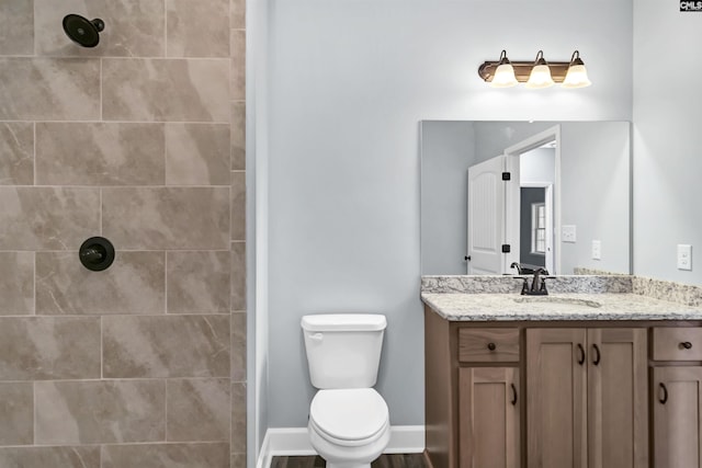 bathroom featuring vanity, toilet, and tiled shower