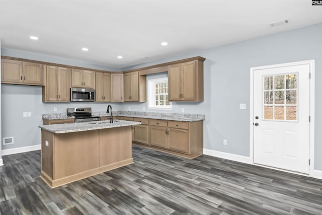 kitchen featuring dark hardwood / wood-style floors, an island with sink, sink, light stone counters, and stainless steel appliances