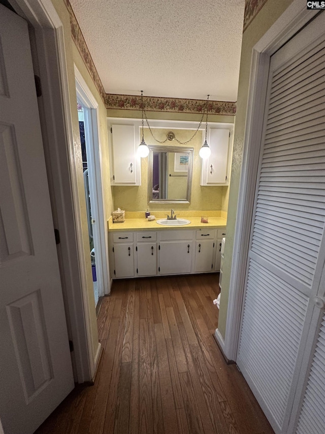 bathroom with hardwood / wood-style flooring, vanity, and a textured ceiling