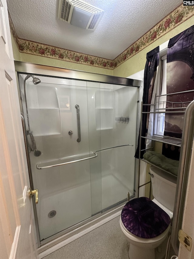 bathroom with a shower with shower door, toilet, and a textured ceiling