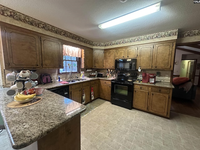 kitchen with sink, a textured ceiling, kitchen peninsula, light stone countertops, and black appliances