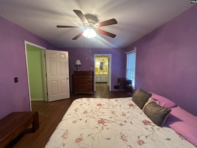 bedroom featuring ceiling fan, a textured ceiling, dark hardwood / wood-style flooring, and ensuite bath