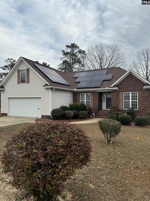 single story home featuring a garage, solar panels, and a front yard