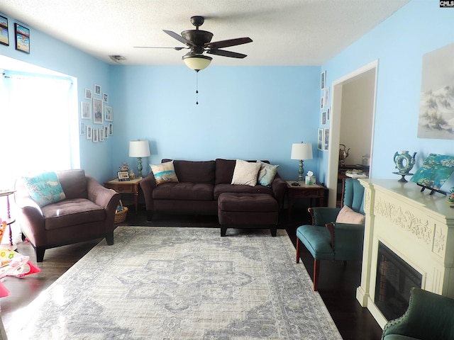 living room featuring ceiling fan, a textured ceiling, and hardwood / wood-style flooring