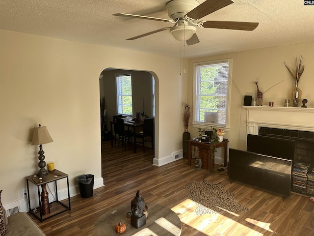 living room featuring ceiling fan, dark hardwood / wood-style floors, and a textured ceiling